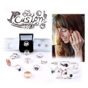 Pu&ograve; includere: Una collezione di anelli e orecchini d'argento con una variet&agrave; di design, tra cui cuori, corone e nodi celtici. I gioielli sono esposti in piccole scatole e su una superficie bianca. La parola "Custom" &egrave; scritta in corsivo su un pezzo di carta sullo sfondo.