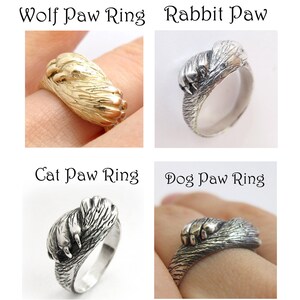 May include: Four silver rings with animal paw designs. The rings are labeled "Wolf Paw Ring", "Rabbit Paw", "Cat Paw Ring", and "Dog Paw Ring".