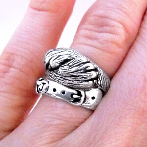 May include: A silver ring featuring a detailed design of a paw print with a belt buckle around it.