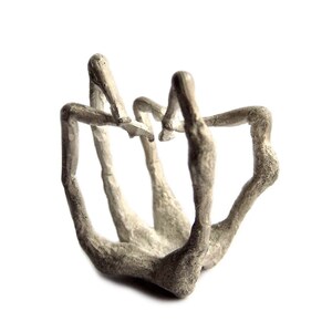Puede incluir: Un anillo de plata con un diseño único y abstracto que se asemeja a dedos entrelazados.