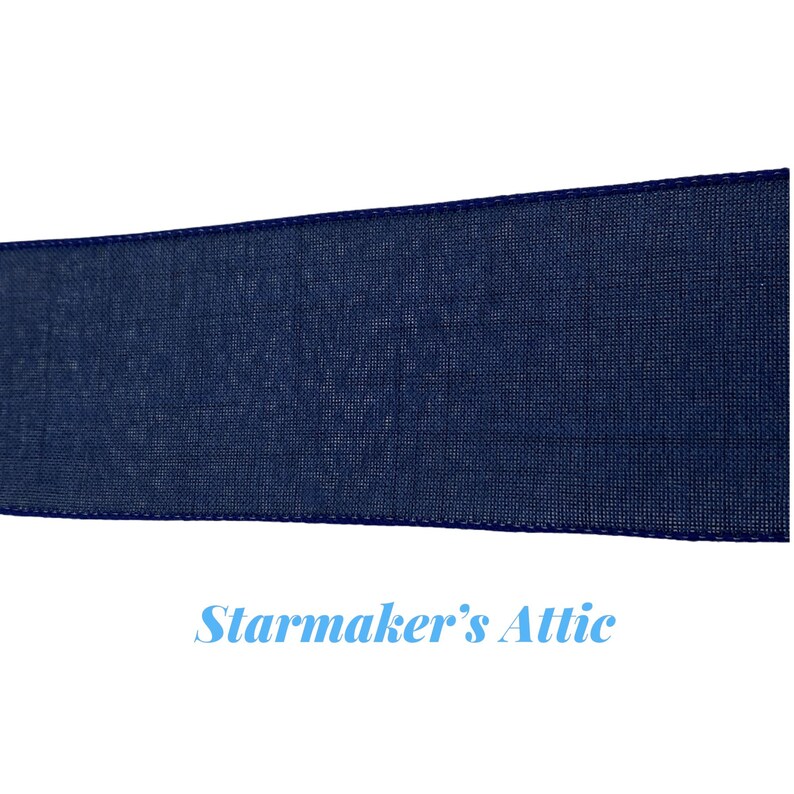 May include: A close-up of a dark blue ribbon with a textured woven fabric. The ribbon has a stitched edge.