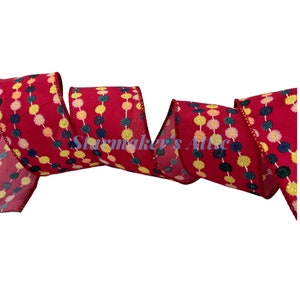 May include: Red ribbon with a repeating pattern of colorful pom-poms and gold glitter. The pom-poms are in shades of pink, yellow, and blue.