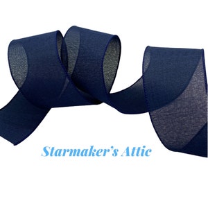 May include: A roll of navy blue sheer ribbon with a textured weave. The ribbon is folded in a loop and has a slight sheen.