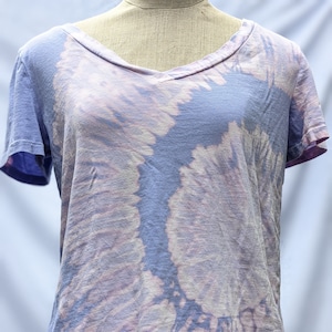 Puede incluir: Una camiseta de cuello en V de color morado y rosa con estampado tie-dye y mangas cortas.