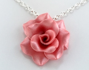 May include: A delicate silver chain necklace with a coral pink rose pendant. The rose is made of polymer clay and has a satin finish.