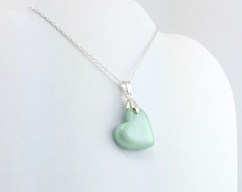 May include: A silver chain necklace with a light green heart-shaped pendant.