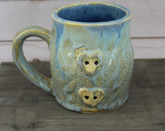 Ceramic Sweater Mug - Light blue green with heart buttons.