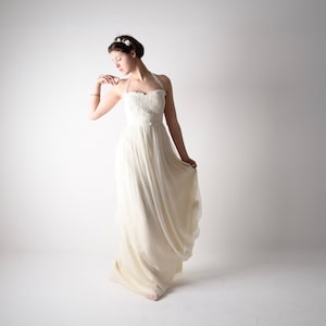 May include: A woman in a white, strapless wedding dress with a flowing skirt. She is wearing a flower crown and has her hair pulled back.
