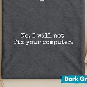 May include: Dark grey t-shirt with the text "No, I will not fix your computer." in white. The shirt has a crew neck and a tag that says "Canvas". The bottom right corner of the shirt has a "Dark Grey" label.