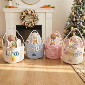 May include: Four Easter baskets in white, light blue, pink, and cream, each with a plush bunny and decorative eggs. The baskets have handles and are personalized with names. A carrot and bunny ears are also featured.