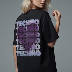 May include: A black short-sleeved t-shirt featuring a large purple heart graphic on the back. The word TECHNO is repeated in a distressed, layered font across the heart and the surrounding area, creating a textured, stacked visual effect.