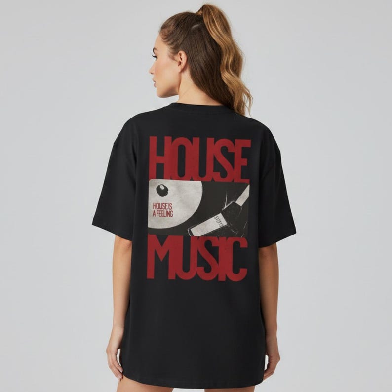 May include: A black short-sleeved t-shirt featuring a graphic on the back with the red text HOUSE MUSIC. Between the words is a white vinyl record illustration with the text HOUSE IS A FEELING and a black and white image of a turntable tonearm.