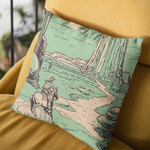 May include: A green and brown throw pillow with a vintage illustration of a cowboy riding a horse through a desert landscape.