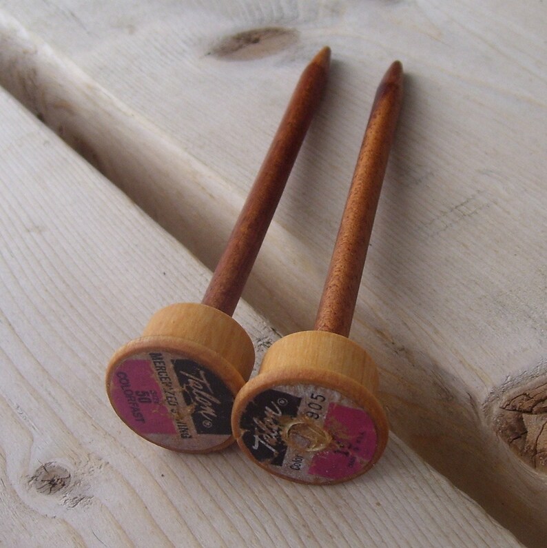 Może przedstawiać: Dwie drewniane druty do rob&oacute;tek ręcznych z brązowymi końc&oacute;wkami i r&oacute;żowymi i białymi etykietami z napisem "Talon" i "Mercerized Knitting 50 Colorfast 305".