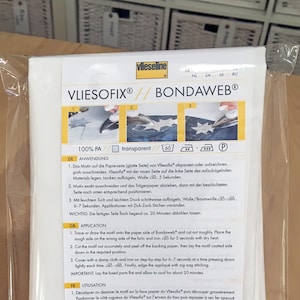 Peut inclure: Instructions pour l'utilisation de Vliesofix Bondaweb, un tissu thermocollant transparent, 100% polyamide. Les instructions sont en allemand, anglais, français et italien. L'image montre une feuille blanche de tissu thermocollant avec un schéma d'utilisation.