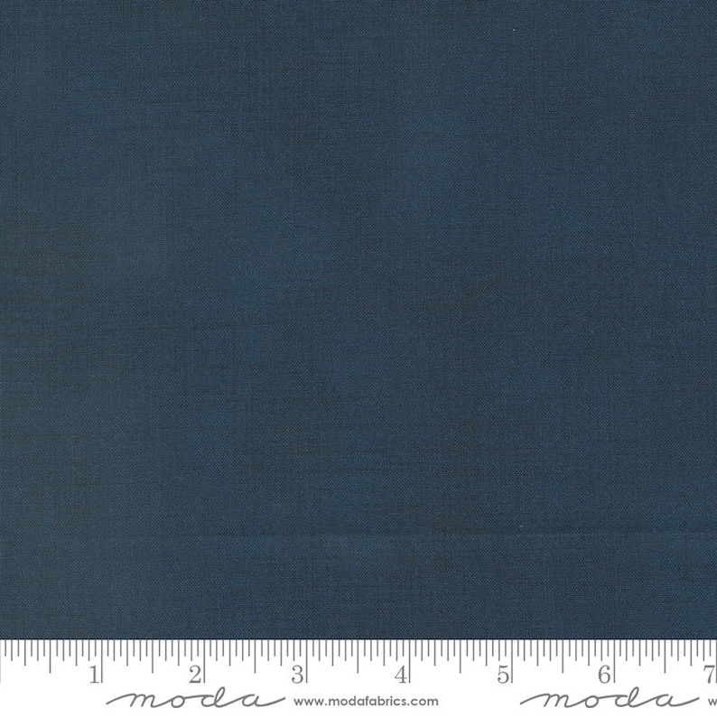 May include: A solid dark blue fabric swatch with a ruler showing 17.8 cm. The ruler has the word "moda" written on it in cursive.