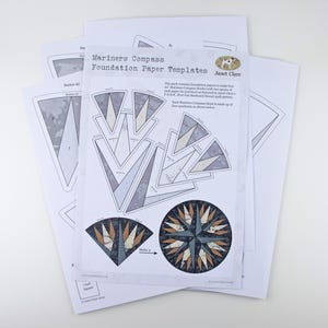 May include: A set of foundation paper templates for a Mariner's Compass quilt pattern. The templates are printed on white paper and feature a compass design with a blue, grey, and white colour scheme. The text on the paper reads "Mariners Compass Foundation Paper Templates" and "Janet Clare".