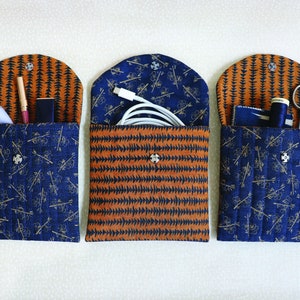 May include: Three fabric pouches with different patterns and closures. The pouches are filled with various items, including a white cord, a pair of scissors, and a small bottle of liquid.