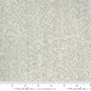 May include: White fabric with a subtle grey and brown speckled pattern. The fabric is textured and has a slight sheen. The fabric is marked with a ruler in inches and the words "moda" and "www.modafabrics.com".