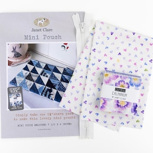 May include: A sewing project kit including a grey instructional pamphlet titled Janet Clare Mini Pouch, a white zip, and two pieces of fabric. One fabric features small purple and pink hearts, while the other is a stack of Delphinium floral squares.