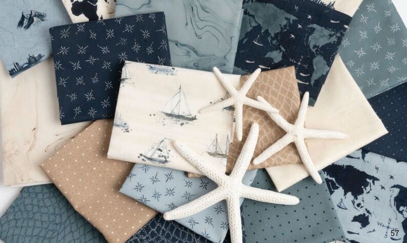 May include: A collection of fabric squares in various shades of blue and brown with white star and nautical patterns. The fabric squares are arranged in a pile with two white starfish on top.