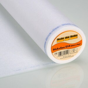 May include: A white roll of fusible interfacing, labelled "Stickvlies/314 sticky-in-foam" with a blue and orange label. The interfacing is used for sewing and crafting.