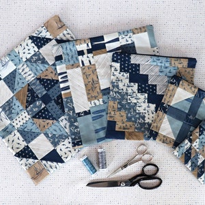 Può includere: Una collezione di pochette in tessuto a tema nautico e un sottobicchiere, con motivi di barche a vela e stelle nei toni del blu, beige e bianco. Sono visibili anche forniture per cucito, tra cui forbici e rocchetti di filo.