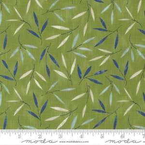 May include: Green fabric with a repeating pattern of blue and white leaves. The fabric is textured and has a subtle sheen. The fabric is shown with a ruler for scale.