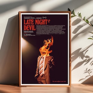 May include: A movie poster for the film "Late Night with the Devil". The poster features a man in a suit with his head on fire. The text on the poster reads "From the Producers of Paranormal Activity and Barbarian" and "Late Night with the Devil". The poster also includes the text "Absolutely Brilliant", "I F*cking Love It", and "It's Midnight's Day After Next". The poster also includes the text "Do not adjust your set."