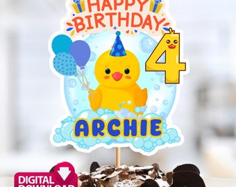 May include: A cake topper featuring a yellow duck with a party hat, balloons, and the number 4. The words "Happy Birthday" and the name "Archie" are also displayed. The topper is placed on a chocolate cake.