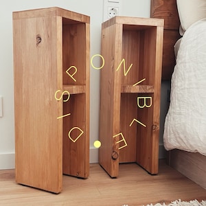 May include: Two wooden nightstands with open shelves, each with two shelves. The nightstands are made of light brown wood and have a natural finish. They are placed next to a bed with white bedding.