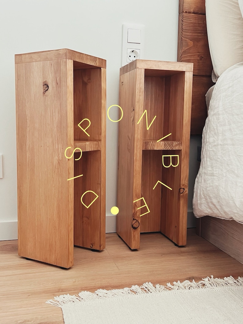 May include: Two wooden nightstands with open shelves, each with two shelves. The nightstands are made of light brown wood and have a natural finish. They are placed next to a bed with white bedding.