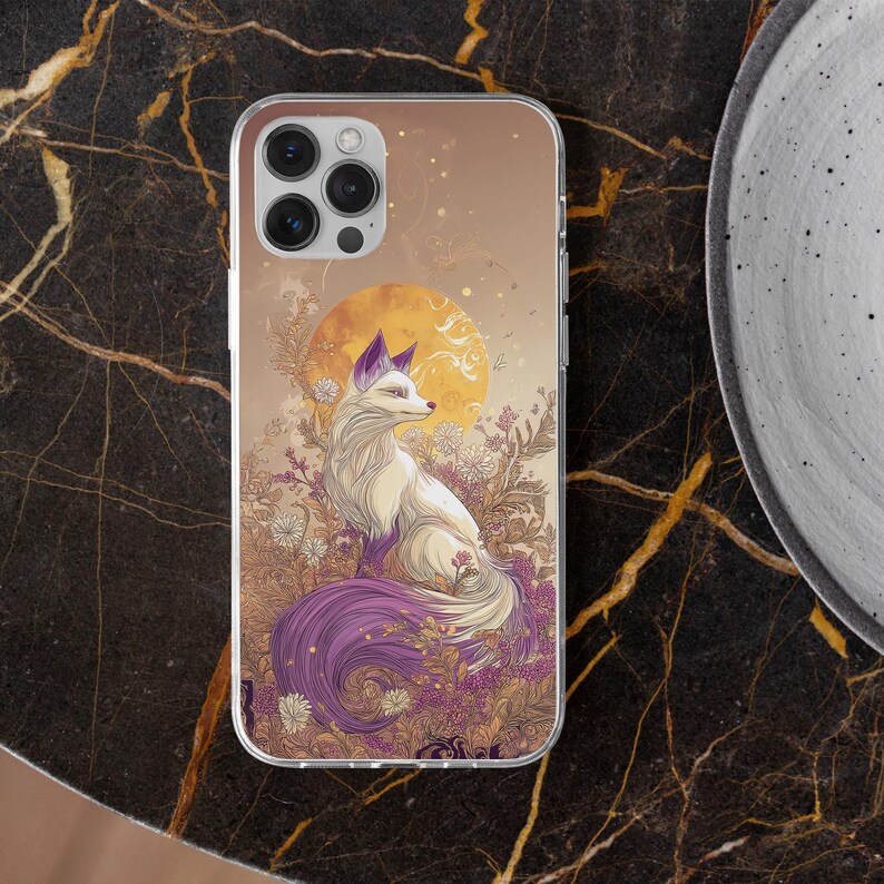 Puede incluir: Funda transparente para tel&eacute;fono con un dise&ntilde;o de un zorro blanco con detalles morados, sentado en medio de flores y una luna llena. La obra de arte tiene una est&eacute;tica de ensue&ntilde;o, con una paleta de colores degradados.