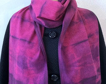 May include: A purple and black tie-dye scarf with a soft, flowing texture. The scarf is folded and draped around a mannequin's neck.