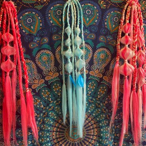 Può includere: Tre ciocche di extensioni per capelli colorate con sezioni intrecciate e pompon morbidi. Le extensioni sono rosa, blu e bianche.