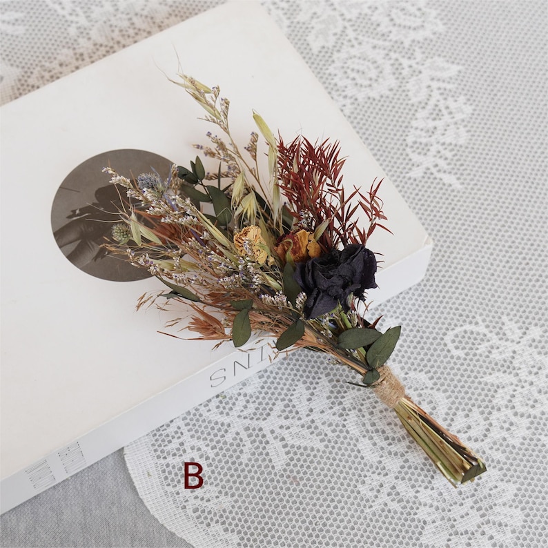 May include: A small bouquet of dried flowers with black, yellow, and brown flowers, and green leaves. The bouquet is tied with twine.