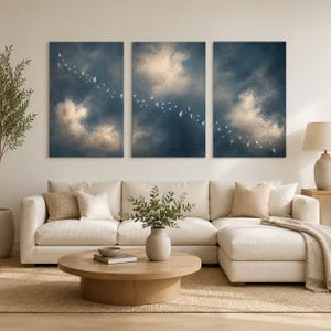 May include: A triptych wall art set featuring three vertical panels depicting a dark blue cloudy sky with a flock of small white birds flying diagonally across the canvases. The artwork displays soft golden light highlights within the clouds.