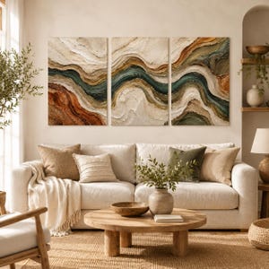 May include: A triptych wall art set featuring three rectangular canvases with thick, textured impasto paint in swirling layers of cream, beige, deep teal, and burnt orange, creating an abstract landscape effect with prominent raised ridges.