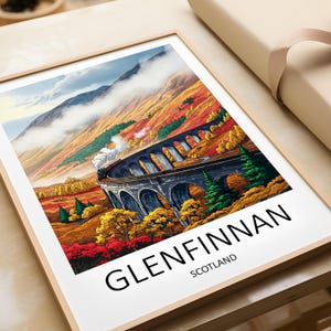 Può includere: Stampa incorniciata con una vivace illustrazione del viadotto di Glenfinnan in Scozia. Un treno a vapore attraversa il ponte in pietra sullo sfondo di un colorato fogliame autunnale e montagne. Il testo "GLENFINNAN SCOTLAND" è visibile in basso.