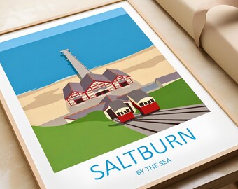 May include: A framed print featuring a stylized illustration of Saltburn-by-the-Sea. The artwork depicts a pier, buildings, and red and white funicular cars against a blue sky and sea. The text "Saltburn by the Sea" is at the bottom.