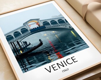 May include: Framed print of Venice, Italy, featuring the Rialto Bridge over a canal. The image shows gondolas, the bridge's arches, and the city's reflection in the water. The word "VENICE" is printed in large, black letters at the bottom.