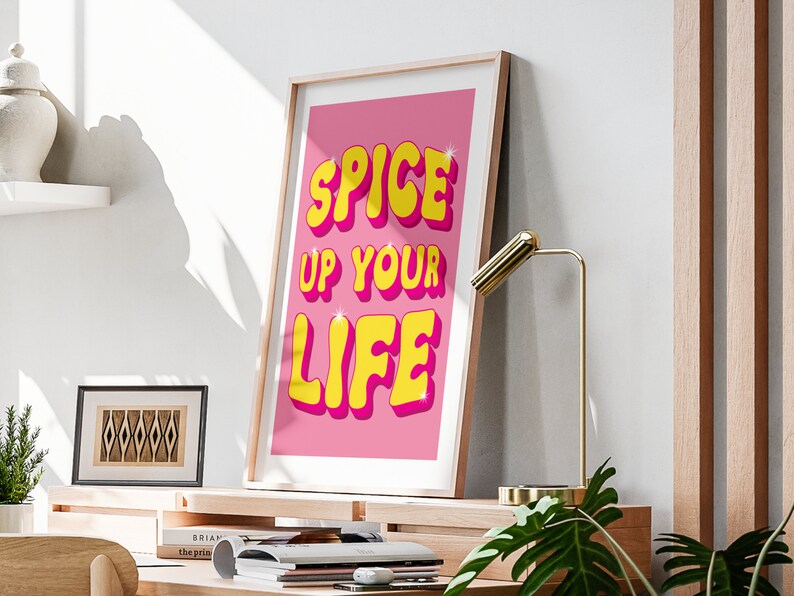 May include: A pink and yellow motivational poster with the text "Spice Up Your Life" in a retro font.