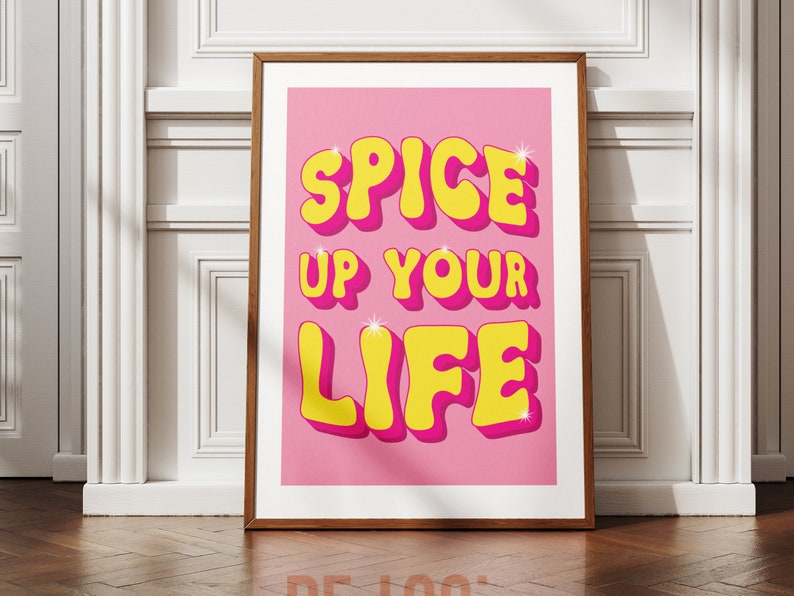 May include: A pink poster with the text "Spice Up Your Life" in yellow 3D letters with a pink outline. The letters have a glossy finish and sparkle.