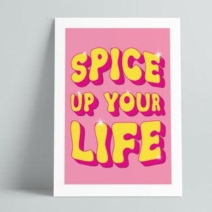 May include: Pink background with the text "Spice Up Your Life" in yellow letters with a pink outline. The letters are in a retro, bubbly font.