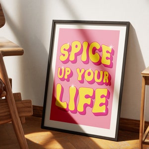 May include: A pink poster with the text "Spice Up Your Life" in yellow, 3D letters with a glittery effect.
