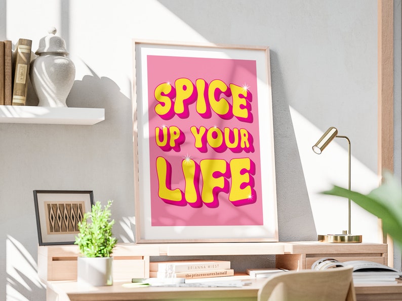 May include: A pink and yellow motivational poster with the text "Spice Up Your Life" in a retro font.