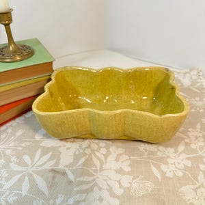 Könnte beinhalten: Eine rechteckige Keramikschale mit gewelltem Rand und einer gesprenkelten, chartreuse-gelben Glasur. Die Schale verfügt über ein tiefes Becken und eine glatte, glänzende Oberfläche, die eine einheitliche Farbe auf der Außen- und Innenseite aufweist.