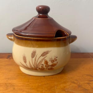 以下が含まれることがあります： 蓋付きのセラミック製スープチューリン。 チューリンはクリーム色で、茶色のバンドと蓋が付いています。 茶色の小麦と花の模様が特徴です。 チューリンには2つの小さなハンドルと、蓋にスプーン用のスロットがあります。