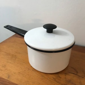 May include: White enamel saucepan with a black handle and lid. The lid has a black knob.