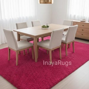 May include: A dining room set with a light wood table and six beige upholstered chairs. The room features a vibrant fuchsia rug, a gold pendant light, and sheer white curtains. A wooden sideboard is visible in the background.